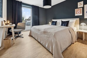Ein modernes Hotelzimmer mit einem großen Bett, einem Schreibtisch und einem Sessel.