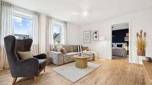 En moderne stue med sofa, lænestol og rundt sofabord.