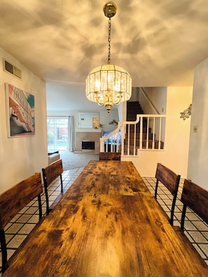 A dining area with a wooden table and benches, a chandelier, a staircase, and a fireplace. - Spacious 6-bedroom house in delightful San Jose with AC (San Jose)