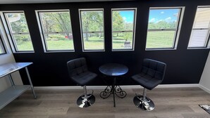 A room with a black wall, four windows, a round table, and two chairs. - The Boyer House Beautiful Modern Farmhouse (Paducah)
