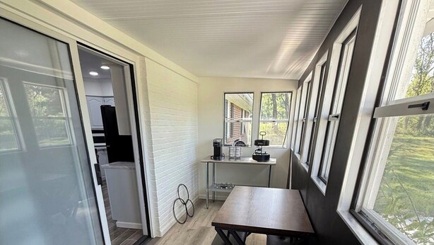 A modern kitchen with a coffee machine, a dining table, and a view of the outdoors. - The Boyer House Beautiful Modern Farmhouse (Paducah)