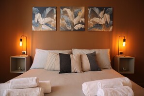 Een hotelkamer met een groot bed, twee nachtkastjes en drie wanddecoraties.