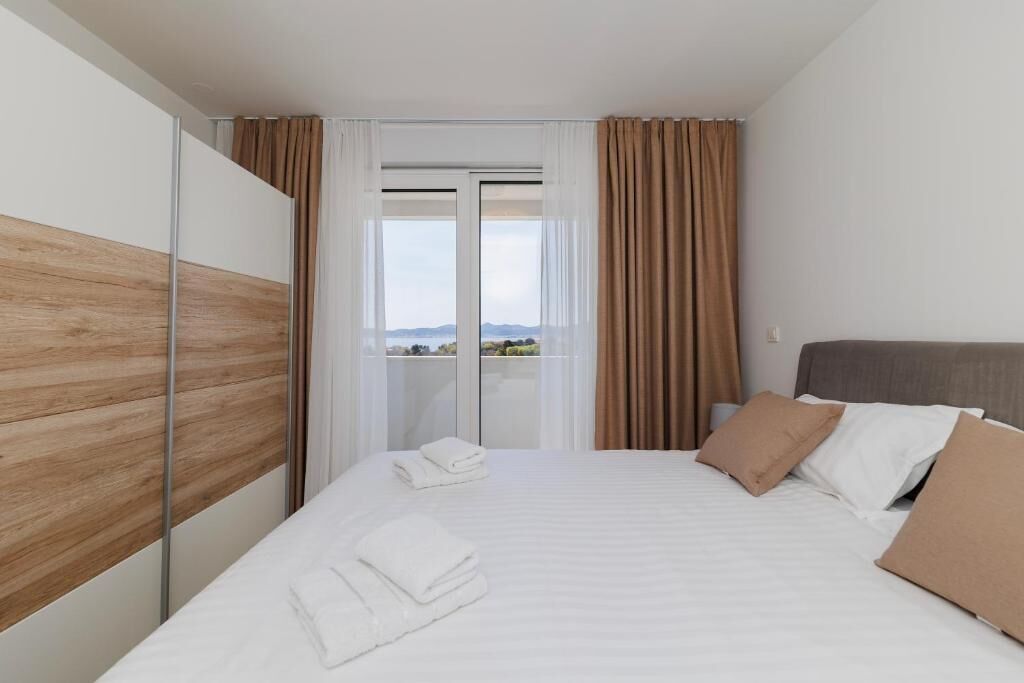 Une chambre d’hôtel avec un lit, des rideaux, une vue par la fenêtre et un panneau en bois au mur.