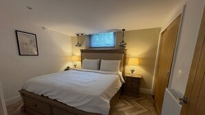 A bedroom with a bed, bedside tables, a window, and a radiator. - Farm House - Sleeps 16 - Hot Tub - Pet Friendly (Skipton)