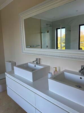 A bathroom with two white sinks, a large mirror, and a toilet. - Wood Road Coastal Guest Rooms  (Hout Bay)