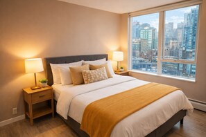 Ein modernes Schlafzimmer mit einem großen Bett, zwei Nachttischen, einem Fenster mit Blick auf die Stadt und einem Beistelltischchen mit einer Lampe.