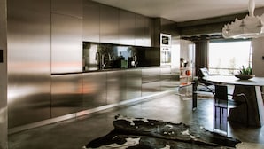 A modern kitchen with stainless steel cabinets, a central island, and a dining area with a round table and chairs.