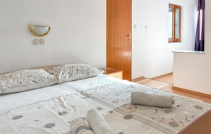 A bedroom with a bed, a bedside table, a wardrobe, and a window with curtains.