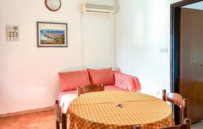 A room with a checkered table, a bed with pink pillows, a framed picture on the wall, and an air conditioning unit. - 2 bedroom pet friendly apartment in Rab (Rab)