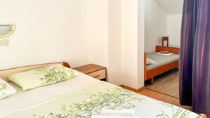 Une chambre à coucher avec un lit, des tables de chevet, un miroir et une fenêtre avec des rideaux.