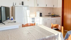 Une cuisine compacte équipée d’un réfrigérateur, d’une cuisinière et d’un évier. On y trouve également une table à manger avec des chaises.