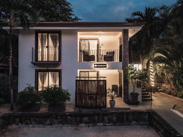 A two-story building with a sign indicating it's a 'Coco Garden Suite.' - King Suite I Ensuite I Kitchenette | Pool, Spa & Patio I Near Beach I Suite One (Del Coco Beach)