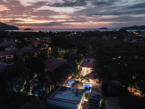 A resort with a swimming pool, palm trees, and a sunset view. - Queen Suite + Single Bed I Full Kitchen I Pool, Spa & Patio I Suite Three (Del Coco Beach)