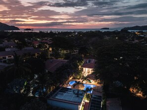 A resort with a swimming pool, palm trees, and a sunset view. - Queen Suite + Single Bed I Full Kitchen I Pool, Spa & Patio I Suite Three (Del Coco Beach)
