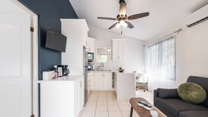 Una cocina moderna con armarios blancos, ventilador de techo y televisor de pantalla plana.