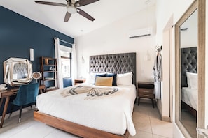 Une chambre à coucher avec un grand lit, un bureau, une chaise, une armoire et un ventilateur de plafond.