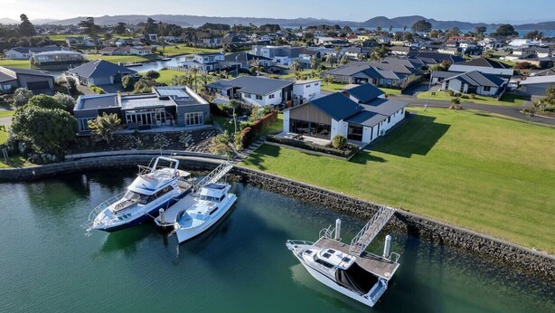 Un quartier résidentiel avec des maisons, un port de plaisance avec des bateaux et une vue dégagée sur le paysage environnant.