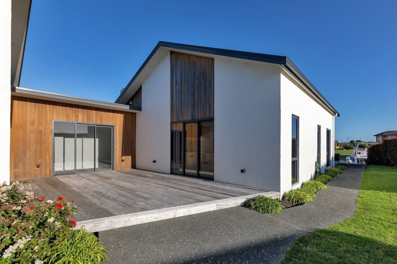 Uma casa moderna com uma garagem espaçosa, um deck de madeira e um gramado bem cuidado.