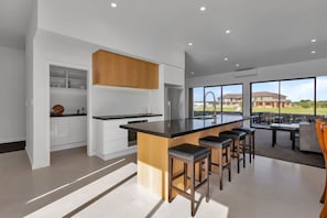 A modern kitchen with a central island, bar stools, and a view of a residential area.