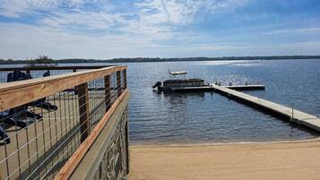 A dock extending into calm water with a wooden railing on one side and a clear sky above.