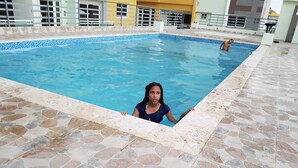 Ein Schwimmbad mit Steinfliesen und einer Person im Wasser.