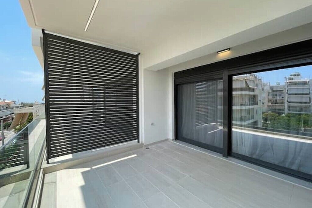 Ein Balkon mit modernem Design, ausgestattet mit einer Glastür und einem Fenster mit horizontalen Jalousien.
