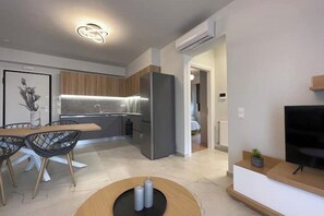 A modern kitchen with a built-in refrigerator, wooden cabinets, and a dining area with a table and chairs. - Athenean Oasis In Ellinikon-C2 (Elliniko)