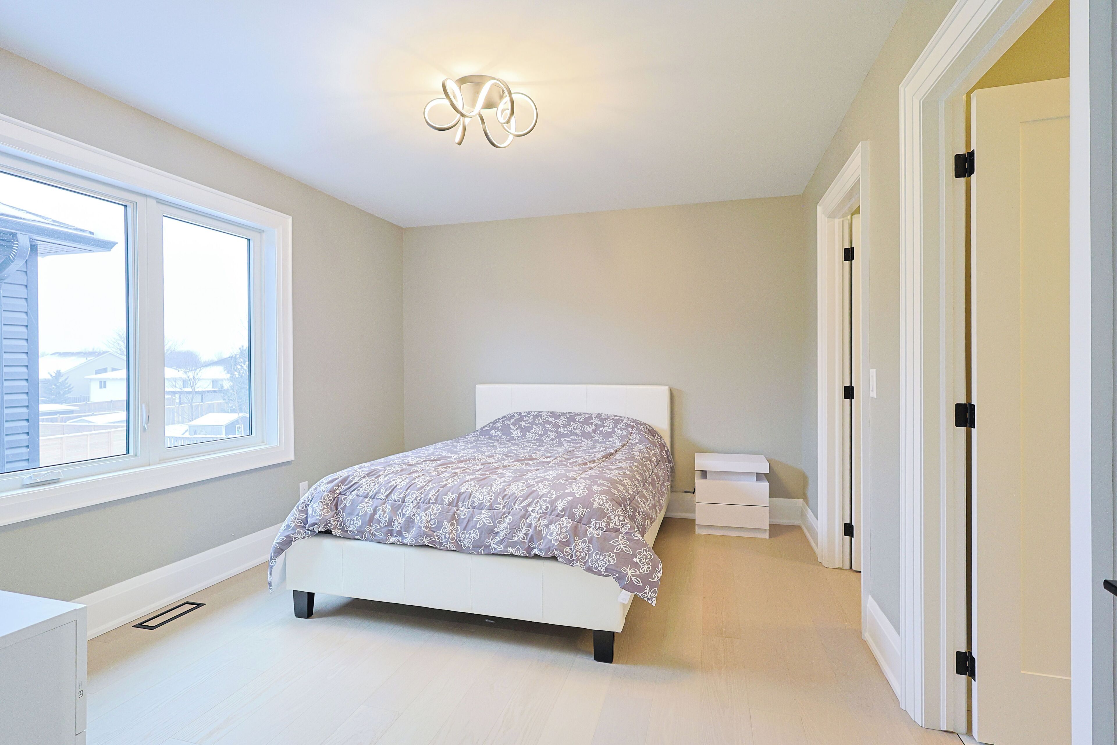 Een slaapkamer met een bed, een raam en een deur.