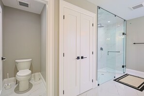Een moderne badkamer met toilet, douchecabine van glas en een witte deur.