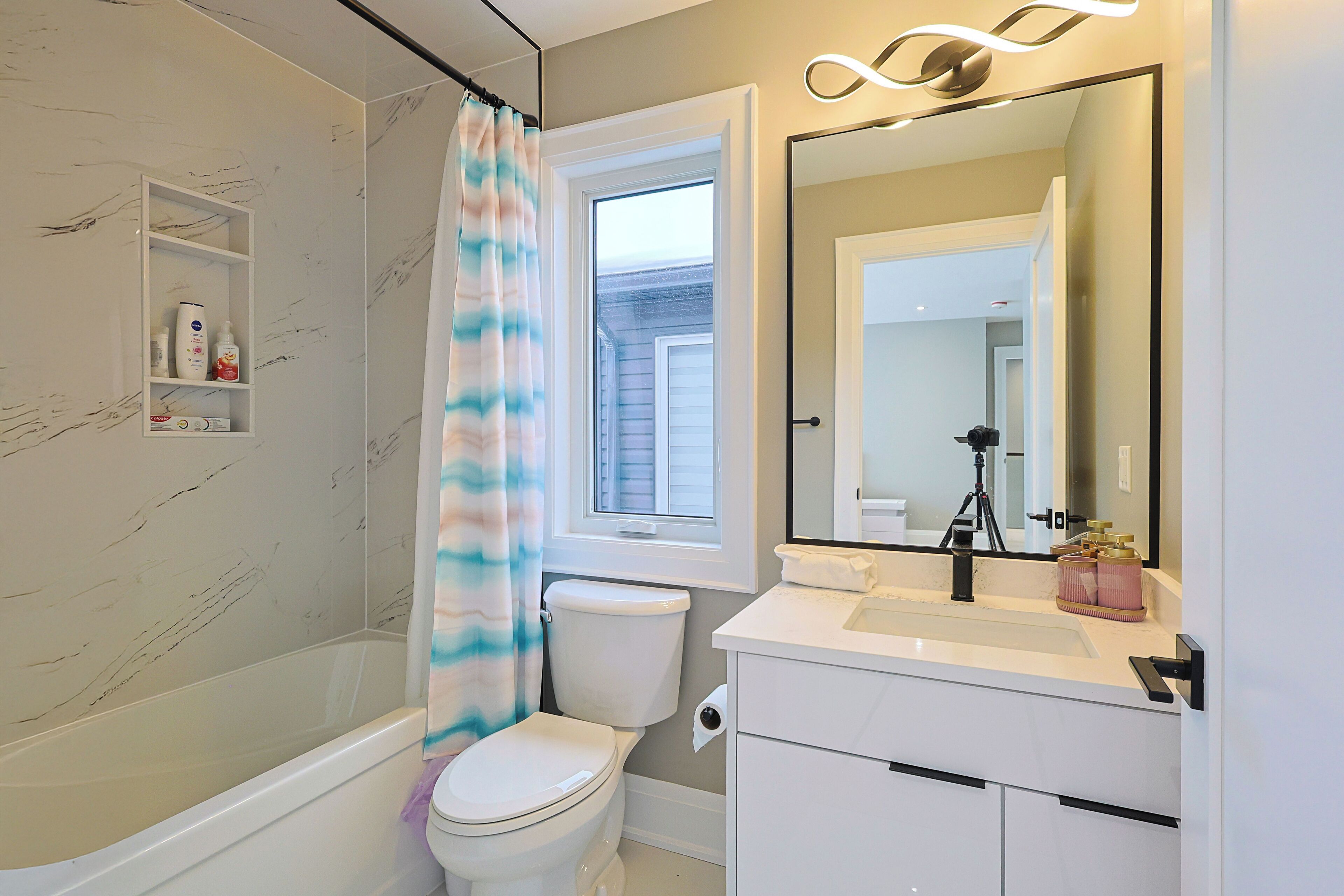 A bathroom with a bathtub, toilet, and a vanity with a mirror.