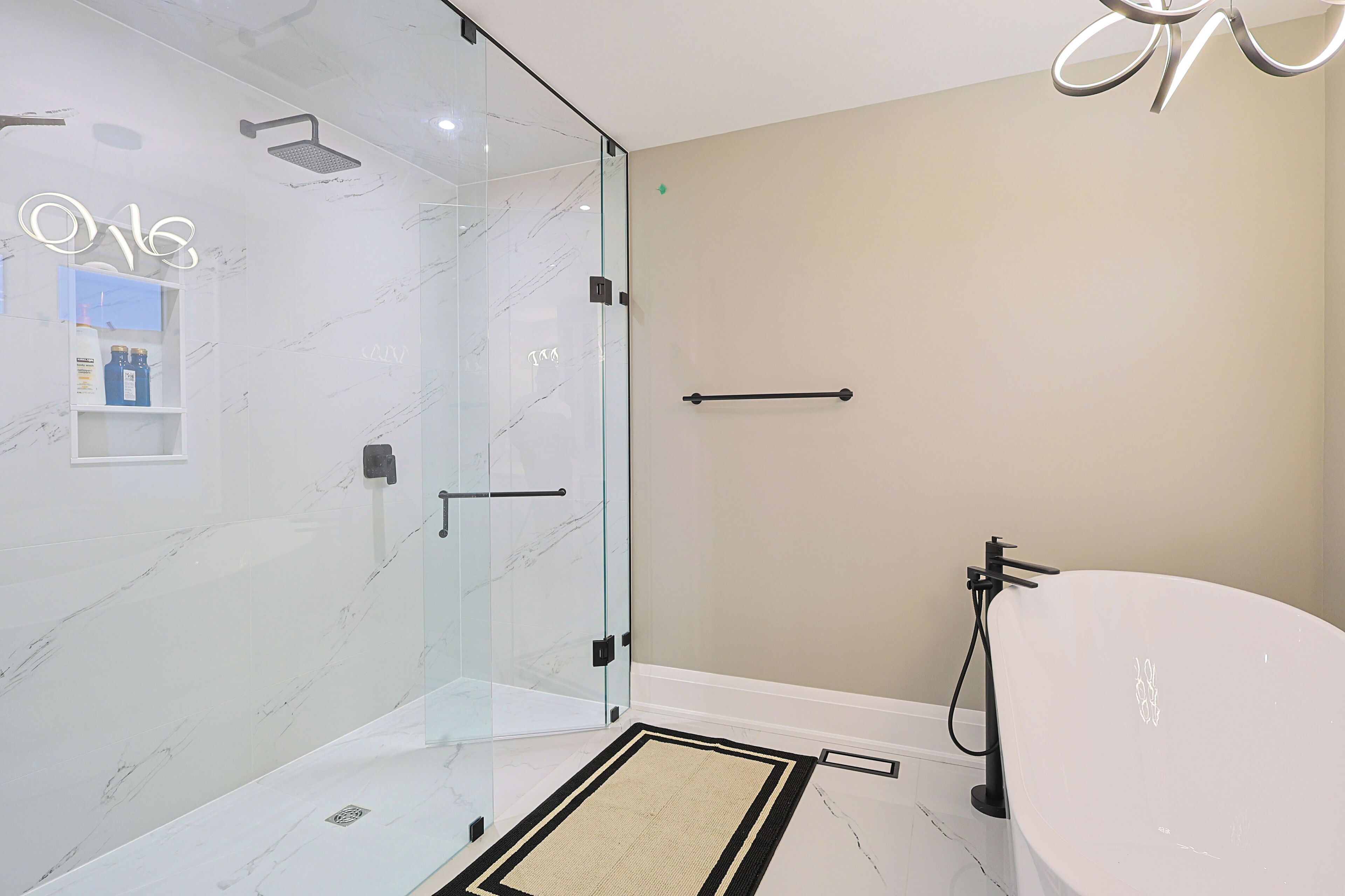 A modern bathroom with a glass shower enclosure, a large bathtub, and a minimalist design.