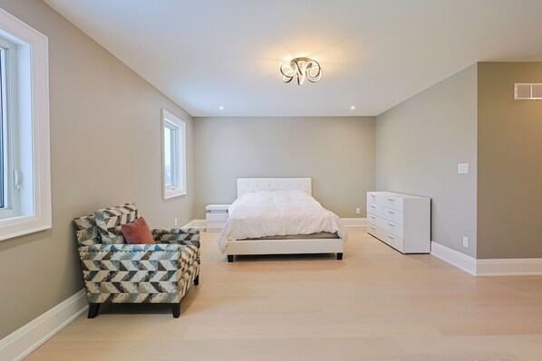 A bedroom with a bed, a dresser, a chair, and a window.