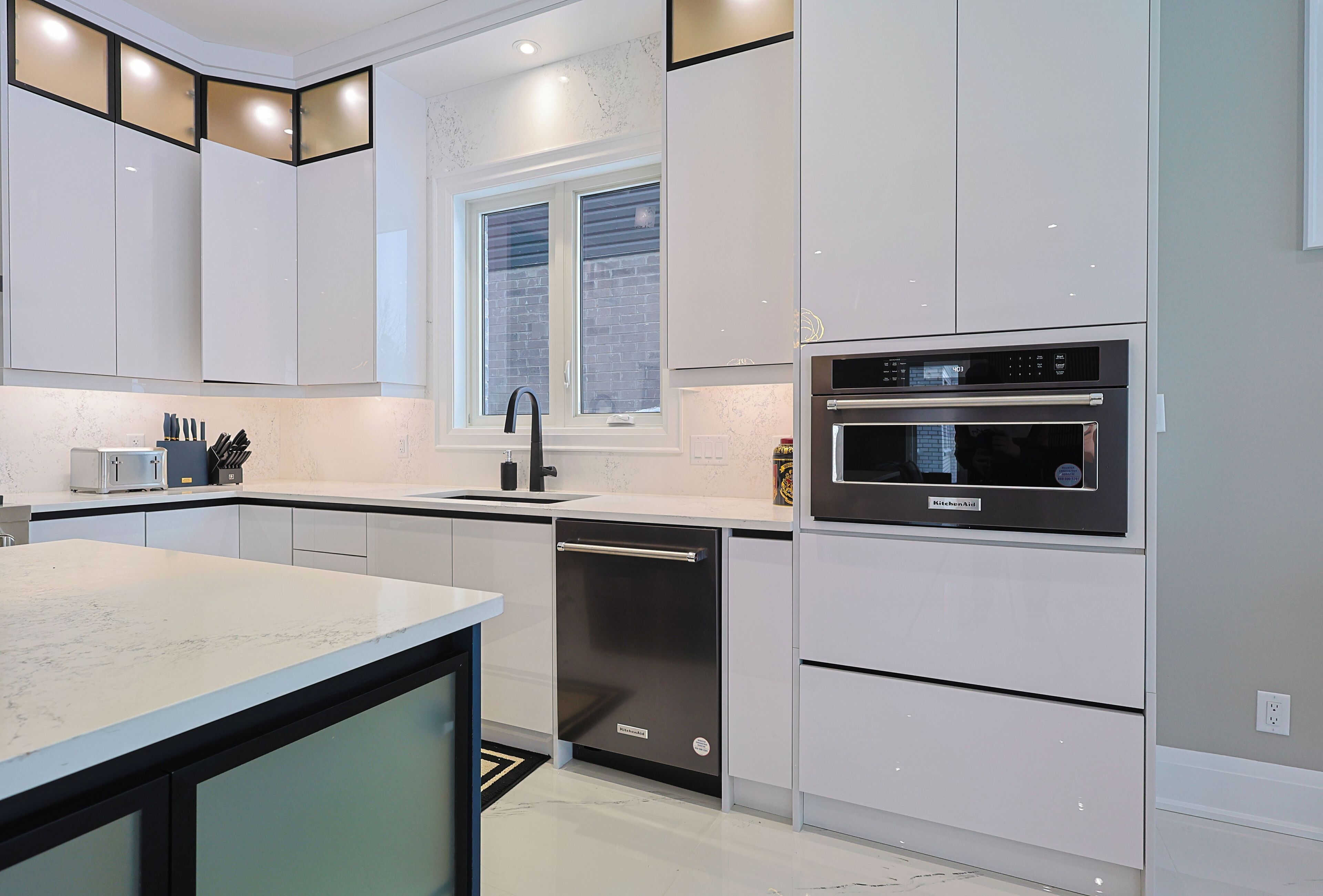 A modern kitchen with white cabinetry, a built-in oven, and a dishwasher.