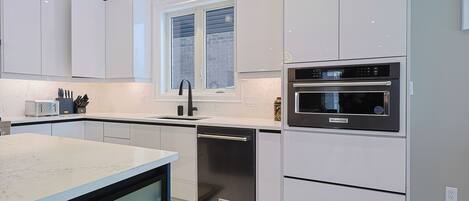 A modern kitchen with white cabinetry, a built-in oven, and a dishwasher.