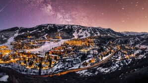 Une ville de montagne enneigée, illuminée la nuit, avec des bâtiments éclairés et des routes sinueuses.