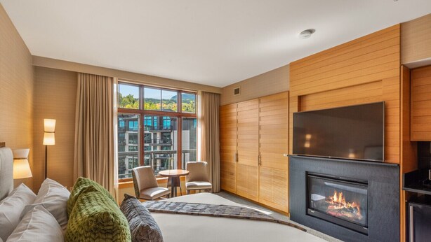 Une chambre d’hôtel comprenant un lit, une cheminée, une télévision, une fenêtre avec vue et un coin salon.