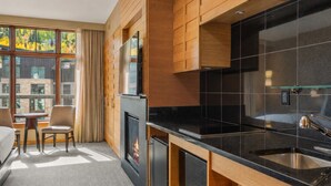 Une cuisine moderne dotée d’une cheminée, de meubles en bois et d’une grande fenêtre offrant une vue sur les arbres.