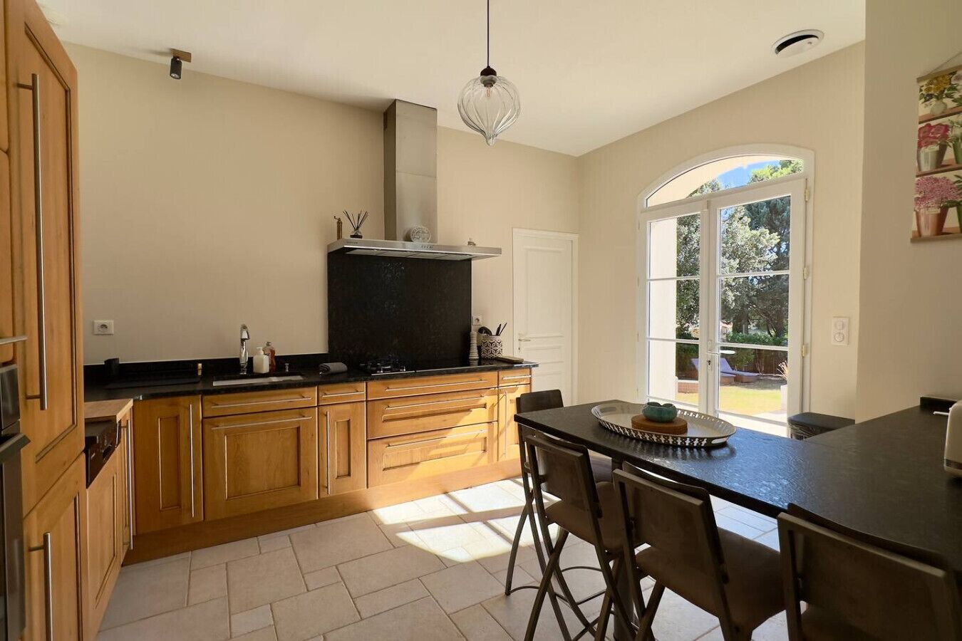 A modern kitchen with wooden cabinets, a black countertop, and a dining area with a table and chairs.