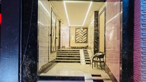A modern entrance with a geometric floor pattern, a staircase leading to an upper level, and a wall-mounted light fixture.