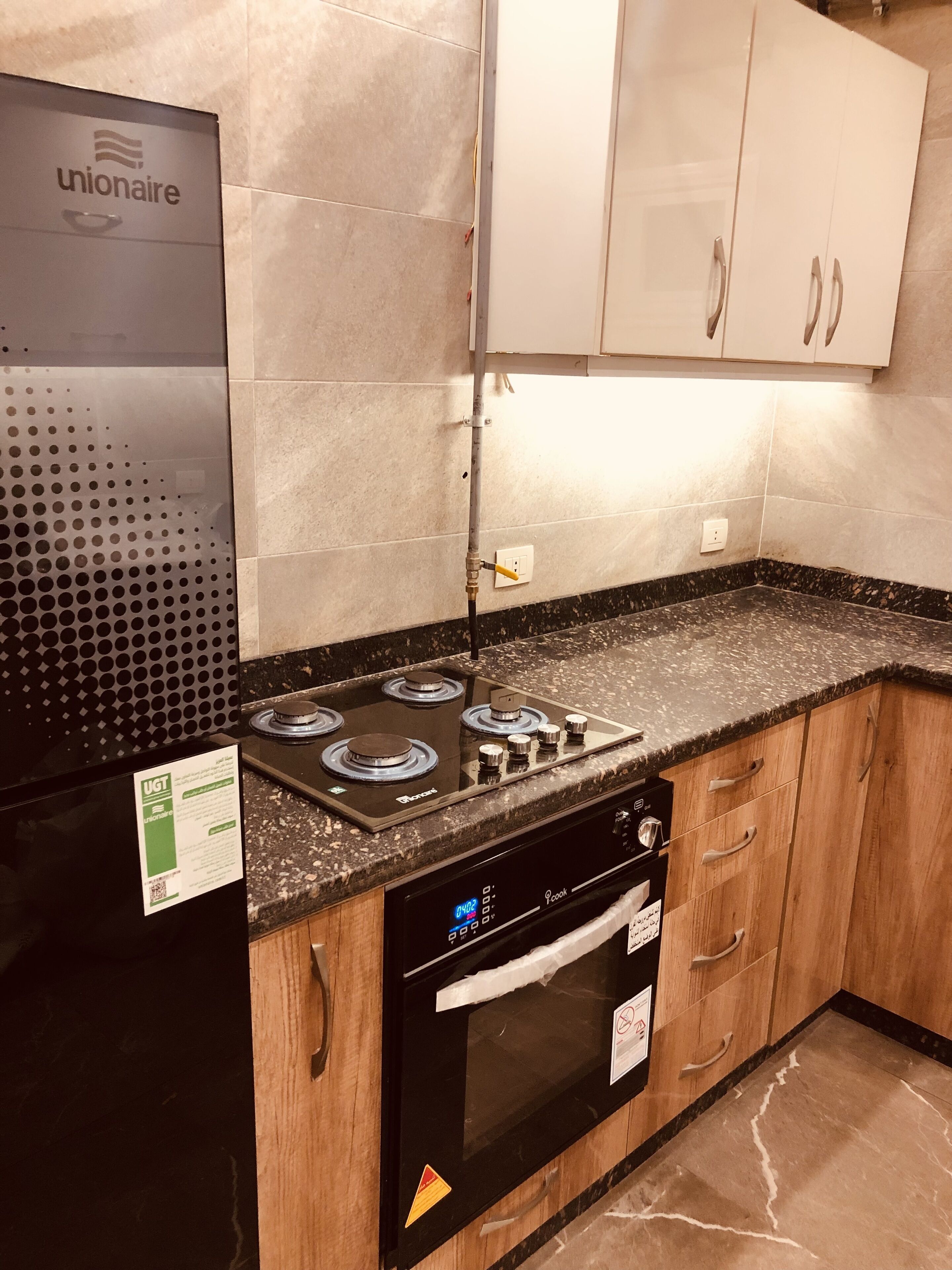 A kitchen with a black stove, oven, and refrigerator, wooden cabinets, and a tiled backsplash.