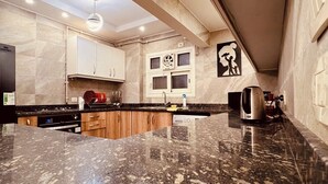 A kitchen with granite countertops, white cabinets, and a ceiling fan.