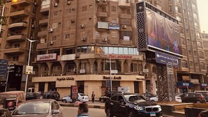 A multi-story building with balconies, air conditioning units, and commercial signage.