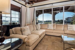 A living room with a sectional sofa, a glass coffee table, and large windows with a view. - Lake Front Luxurious House in Reunion Resort (Kissimmee)
