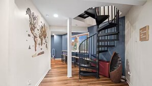 A modern interior with a spiral staircase, wooden flooring, and a wall with various small items. - The Lazy Lodge: Peaceful Retreat 15 mins from Downtown Greenville (Easley)