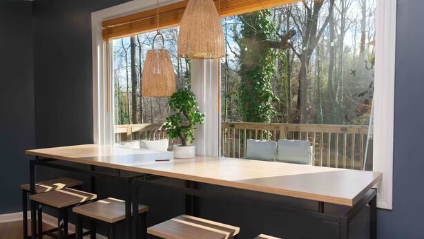 A kitchen with a large island, wooden stools, hanging wicker lamps, and a view of trees through a window. - The Lazy Lodge: Peaceful Retreat 15 mins from Downtown Greenville (Easley)