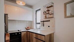A modern kitchen with white cabinets, a black oven, a wooden countertop, a sink, and a window. - Cozy 1-bedroom apartment in the heart of Tirana (Tirana)