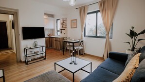 A modern living room with a sofa, a coffee table, a TV, and a dining area with a table and chairs. - Cozy 1-bedroom apartment in the heart of Tirana (Tirana)