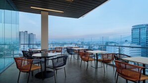Eine Dachterrasse mit Tischen und Stühlen und Blick auf die Stadt.