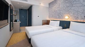 A hotel room with two beds, a map wall, a mirror, and a small bathroom area.