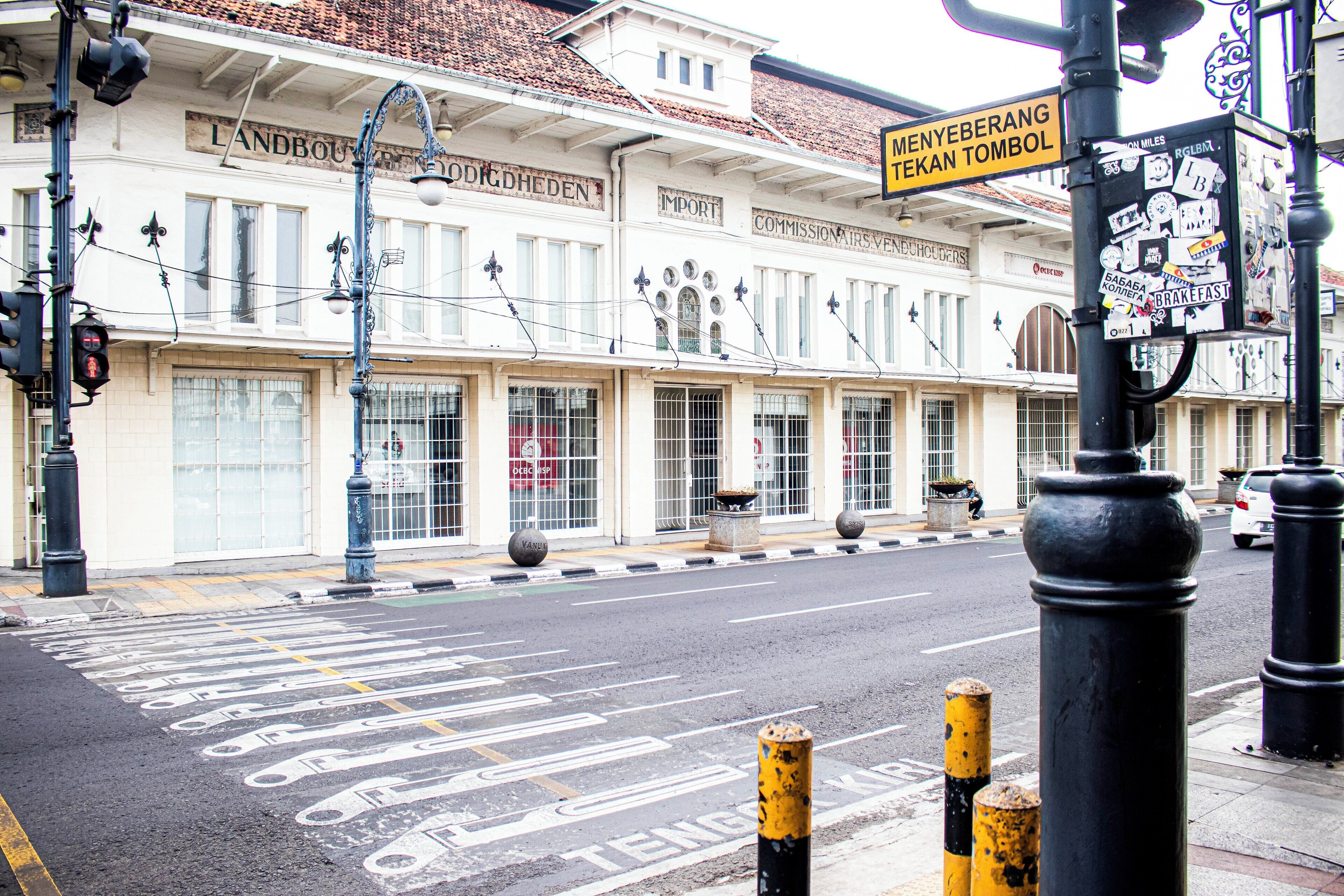 A building with large windows, a sign reading 'Landbou', and a street with marked lanes.
